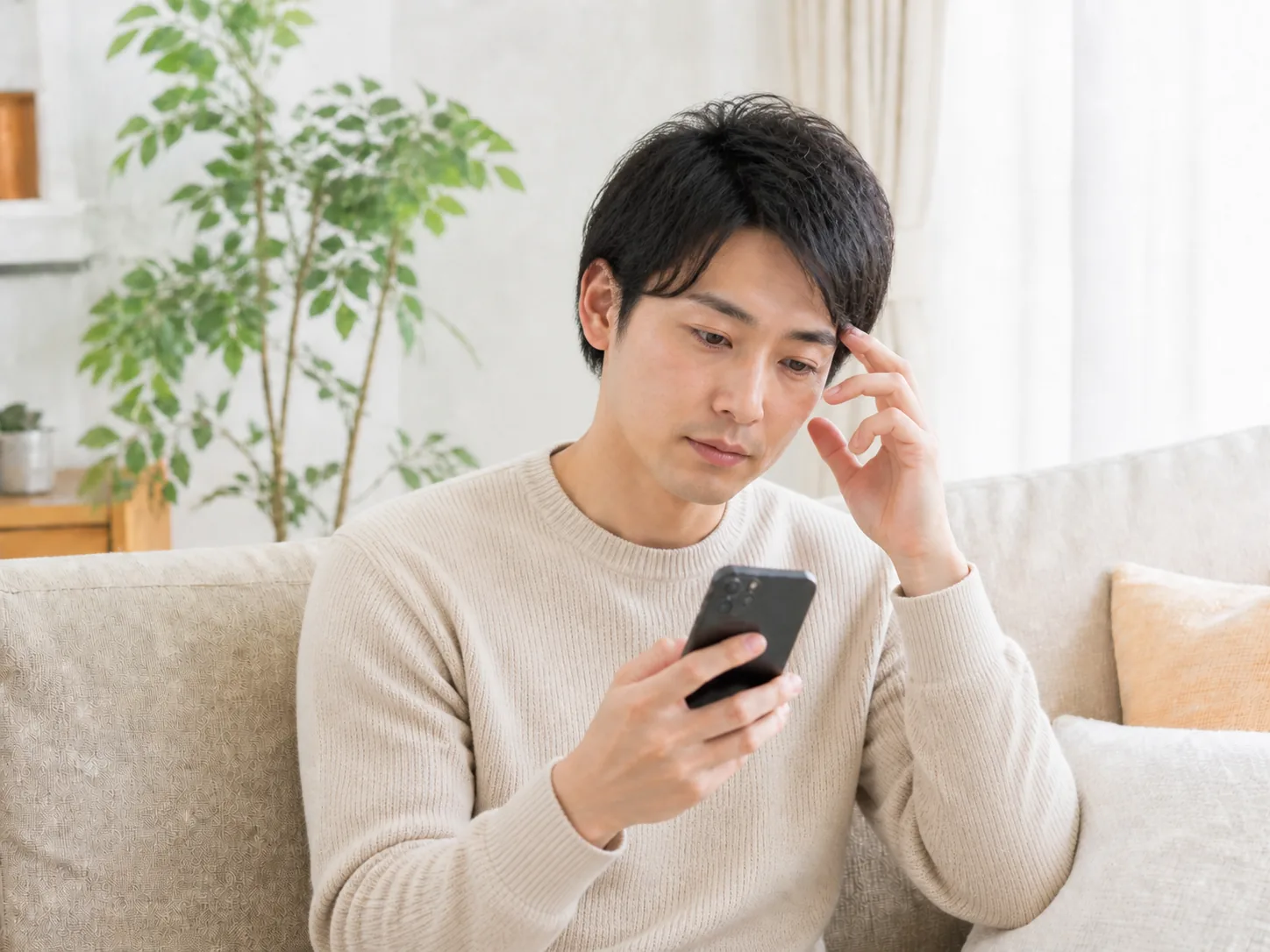 スマートフォンを見て婚活に悩む男性のイメージ